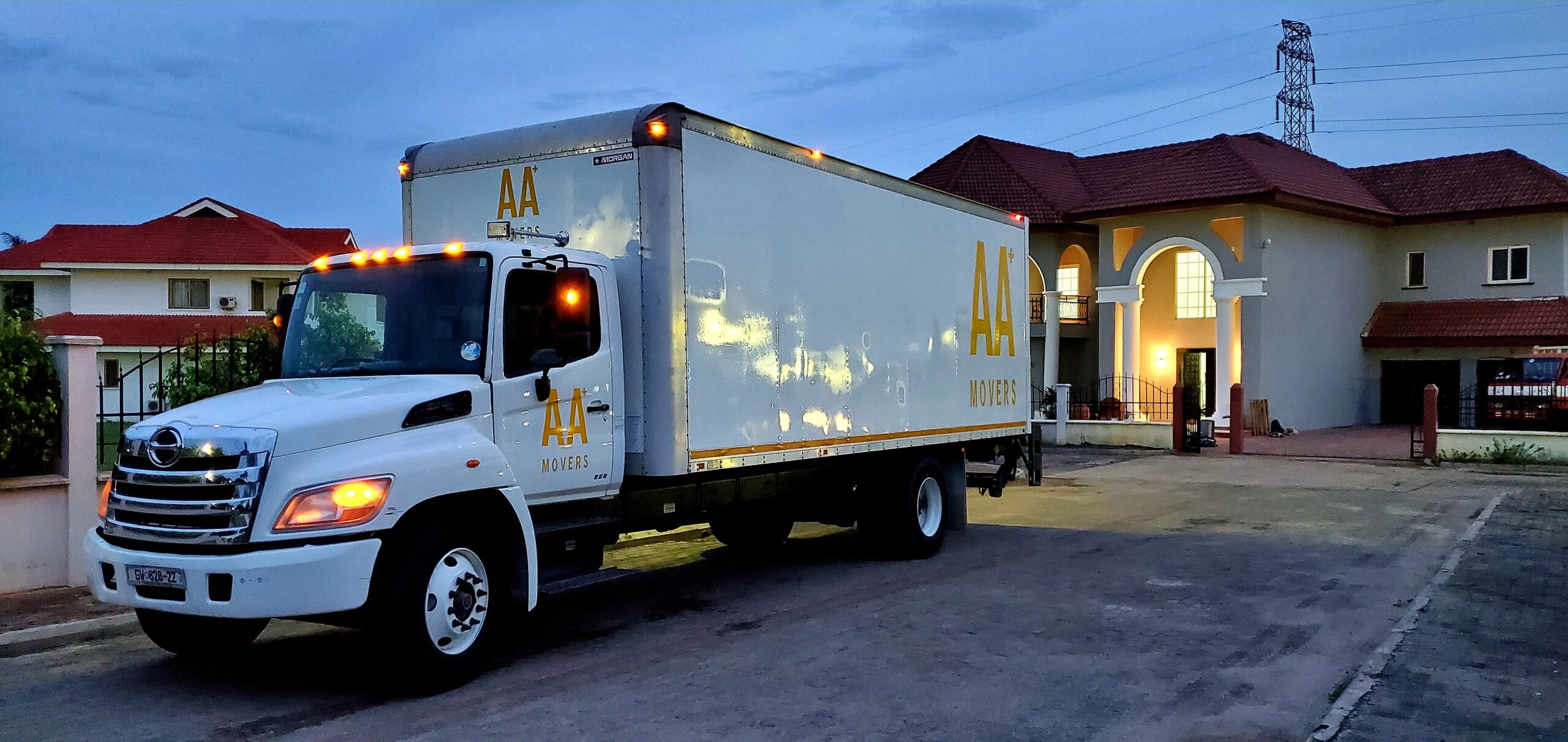 AA+ Movers branded 24-foot truck with tail lift parked at Trasacco Valley, Adjiringanor, during a residential move.