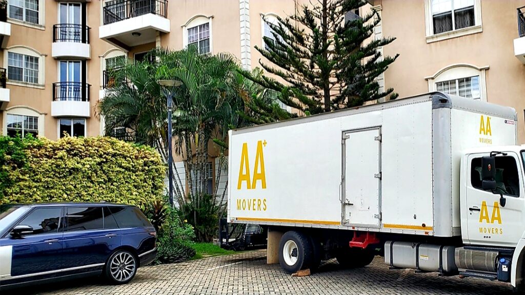 AA+ Movers 24-foot box truck with tail lift parked at Astoria Palms in the Airport Residential Area, Accra, during a move.