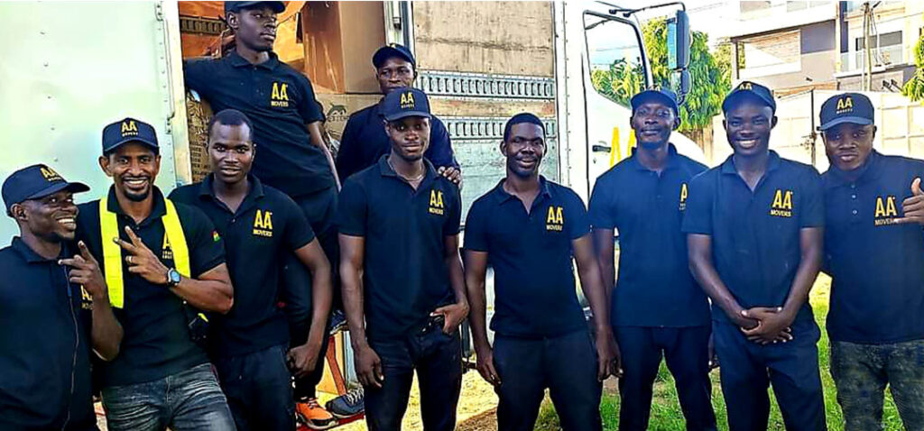 AA+ Movers team, fully uniformed, standing proudly in front of a 24-foot moving truck, ready for professional moving services in Accra