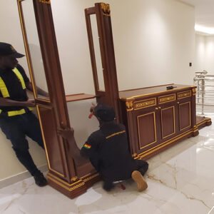 "Premier moving services in Ghana by AA+ Movers, showcasing movers reassembling a glass cabinet after a move in East Legon, Accra."