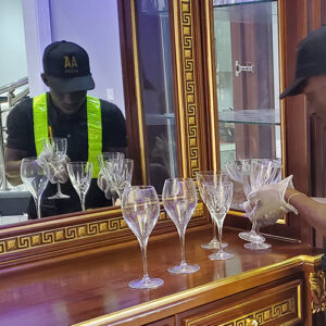 "Premier moving services in Ghana by AA+ Movers, featuring a uniformed mover wearing gloves for hygiene as he carefully removes champagne and glassware from a cabinet during a move in Airport Hills, Accra."